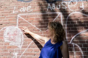 Gwen-Konings-Wijst-Naar-Grafittitekst-LOVE-in Zon-versus-Abuse-in-Schaduw